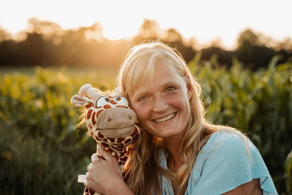 Maria Rosenburg lächelt mit ihrer Handpuppe Gerda im warmen Abendlicht